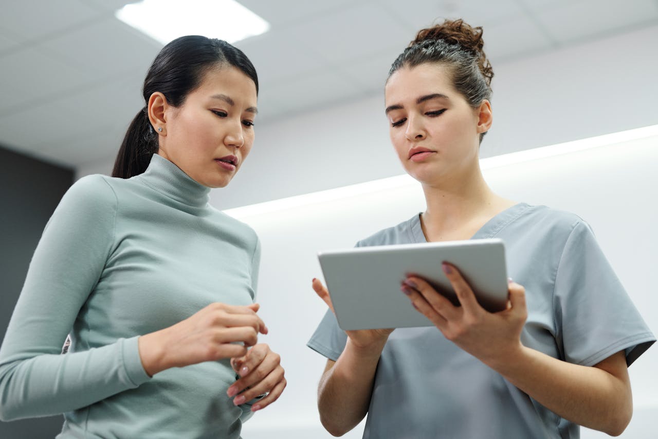 portfolio-05 Two women engaged in a healthcare consultation using a digital tablet indoors.
