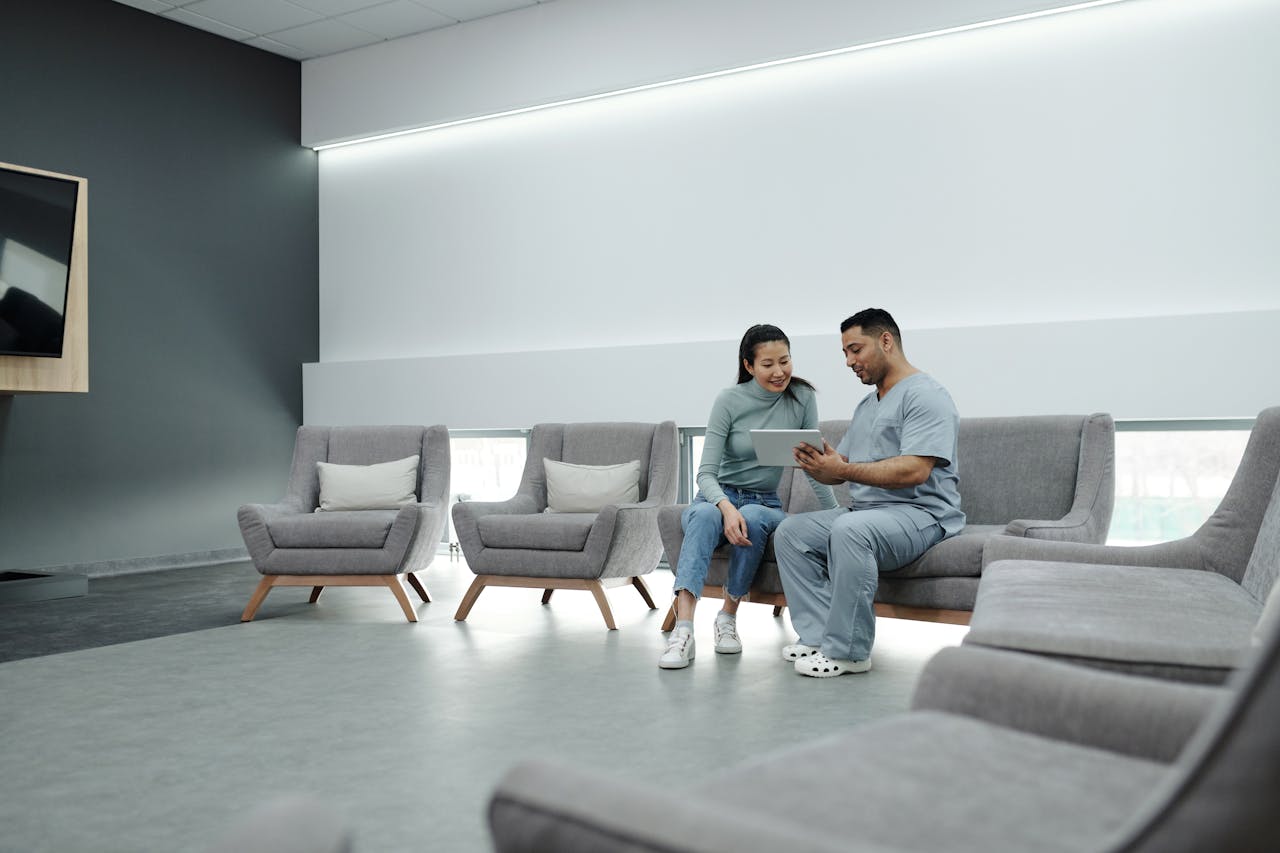 core-values A doctor in scrubs consulting with a patient in a modern, indoor waiting area.