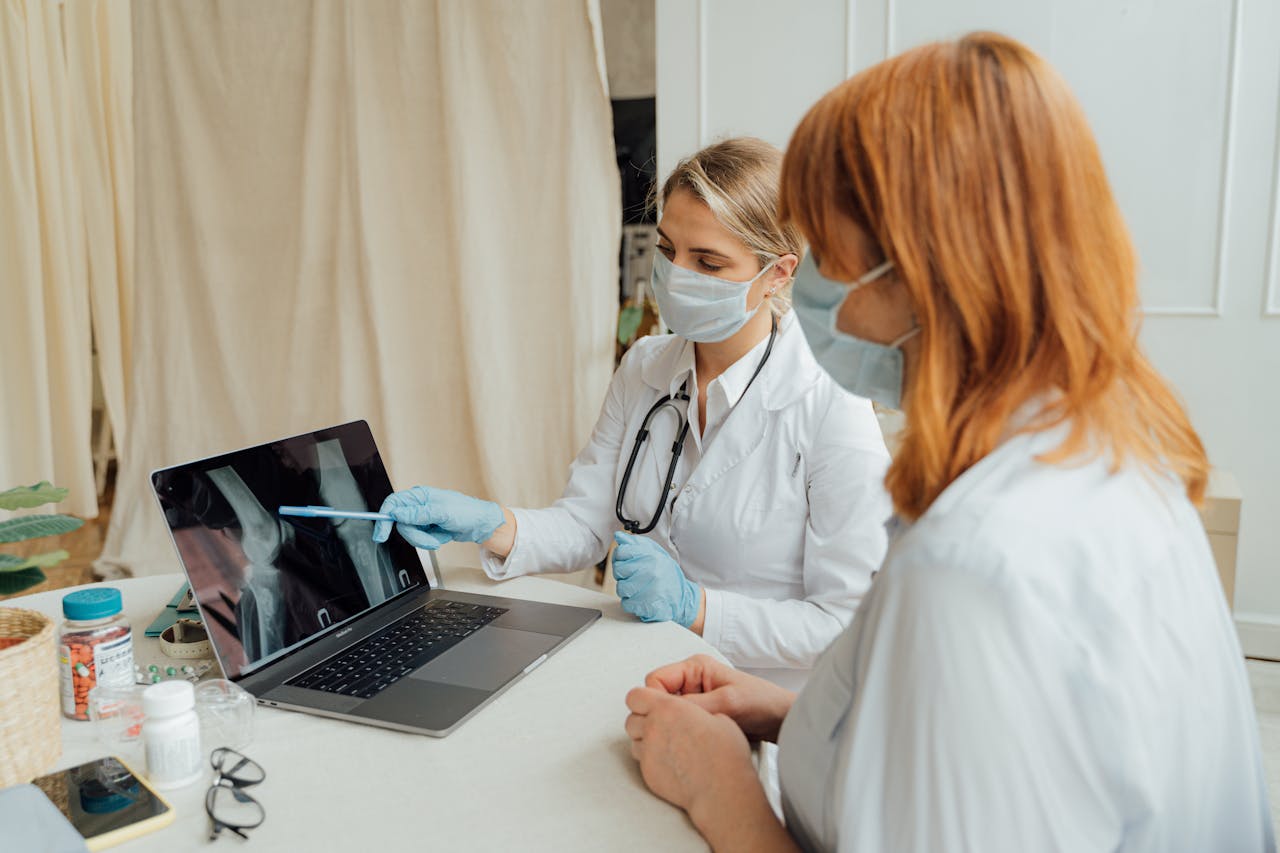 creative-approach-img Doctor explains X-ray results to patient using a laptop in a clinic setting.